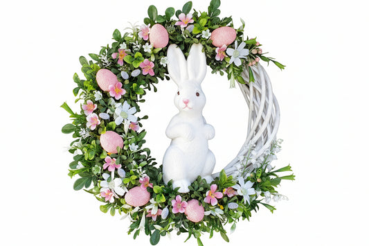 Decorative white grapevine Easter wreath with a white rabbit figure, pink eggs, and flowers