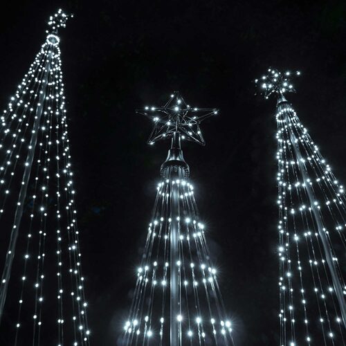 Close-up nighttime view of cool white animated LED Christmas light show trees displaying different lighting patterns.