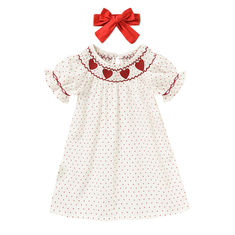 White dress with red heart patterns and a matching red bow on a white background valentines Day baby toddler