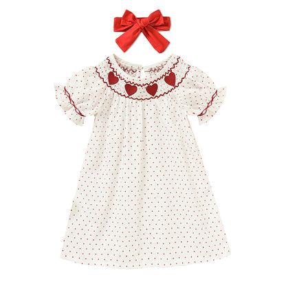 White dress with red heart patterns and a matching red bow on a white background valentines Day baby toddler