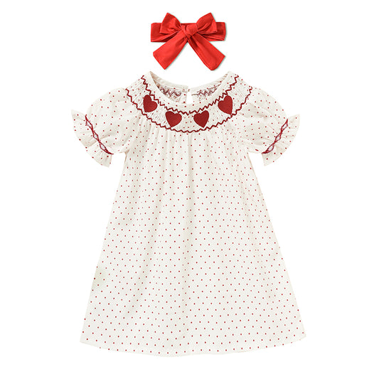 White dress with red heart patterns and a matching red bow on a white background valentines Day baby toddler