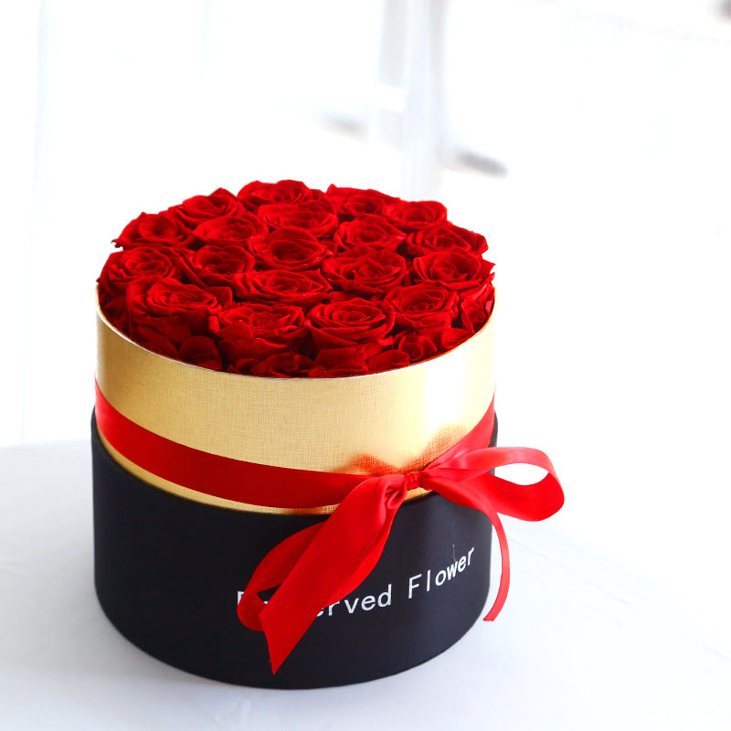 Round box with red roses and a red ribbon on a white background