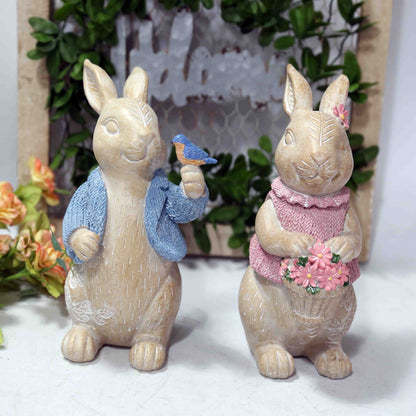 decorative rabbit figurines, one with a blue scarf and bird, the other with a pink dress and flowers resin bunny statues