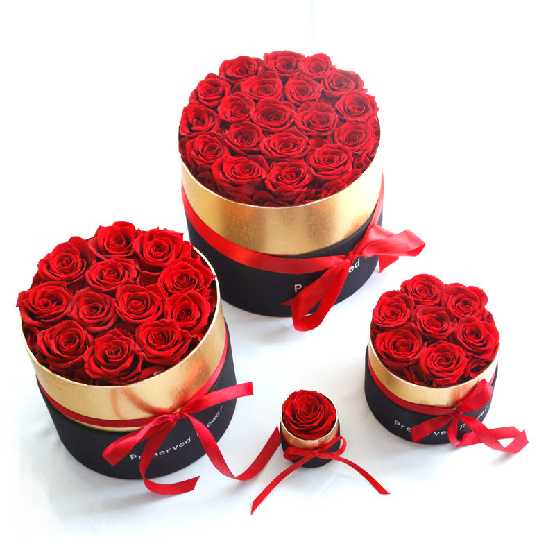 Three round boxes filled with red roses on a white background