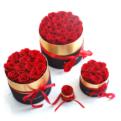 Three round boxes filled with red roses on a white background