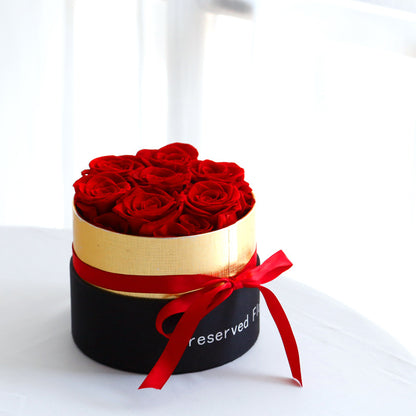 Round black box with red roses and a red ribbon on a white background