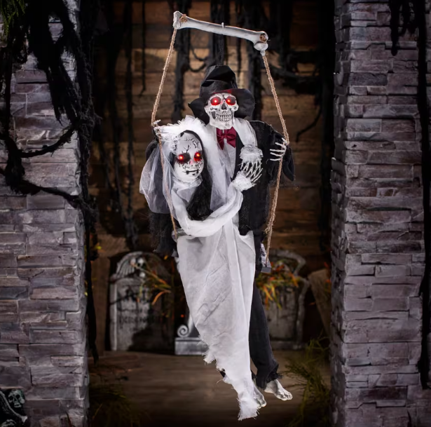 Halloween decoration of a skeleton couple with a tombstone in a spooky setting.