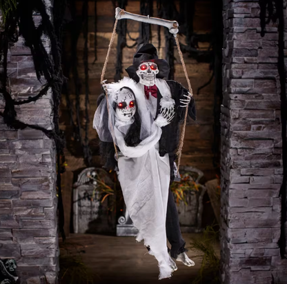 Halloween decoration of a skeleton couple with a tombstone in a spooky setting.