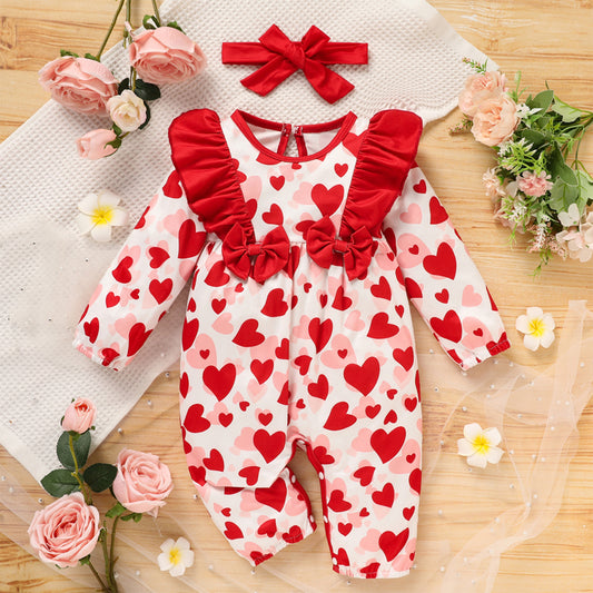 Baby romper with red hearts and ruffles on a wooden surface with flowers Valentines Day