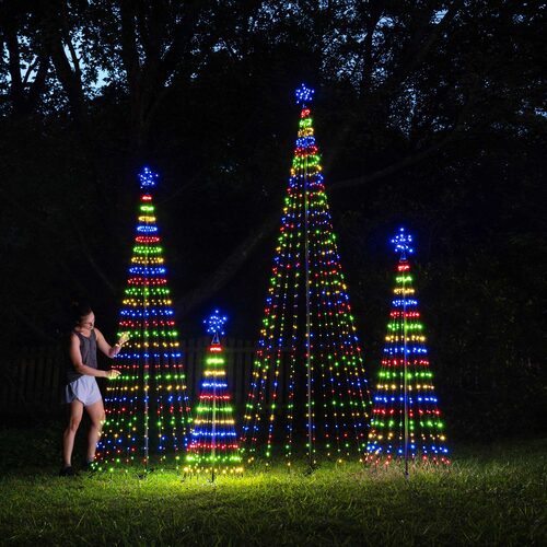 Multiple multicolor animated LED Christmas light show trees of different heights illuminated outdoors at night.