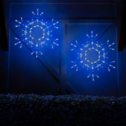 Two matching 36-inch blue and cool white LED folding snowflakes illuminated together in an outdoor Christmas decorating display.