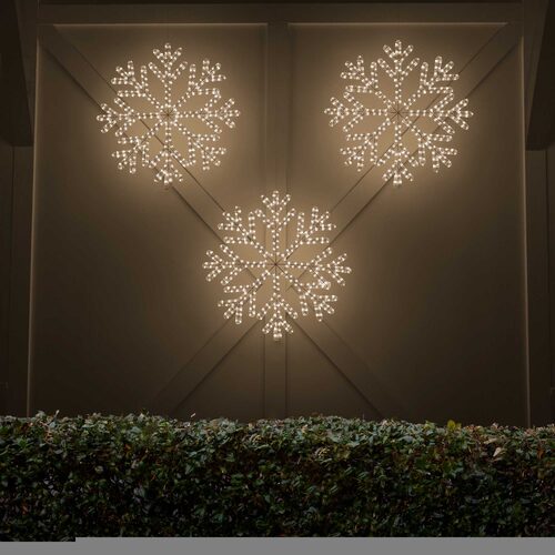 Warm white LED snowflake Christmas decorations illuminated outdoors at night, showing an elegant holiday lighting display.